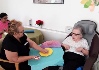 Staff and Abbotsleigh Care Home resident crafting with coloured paper