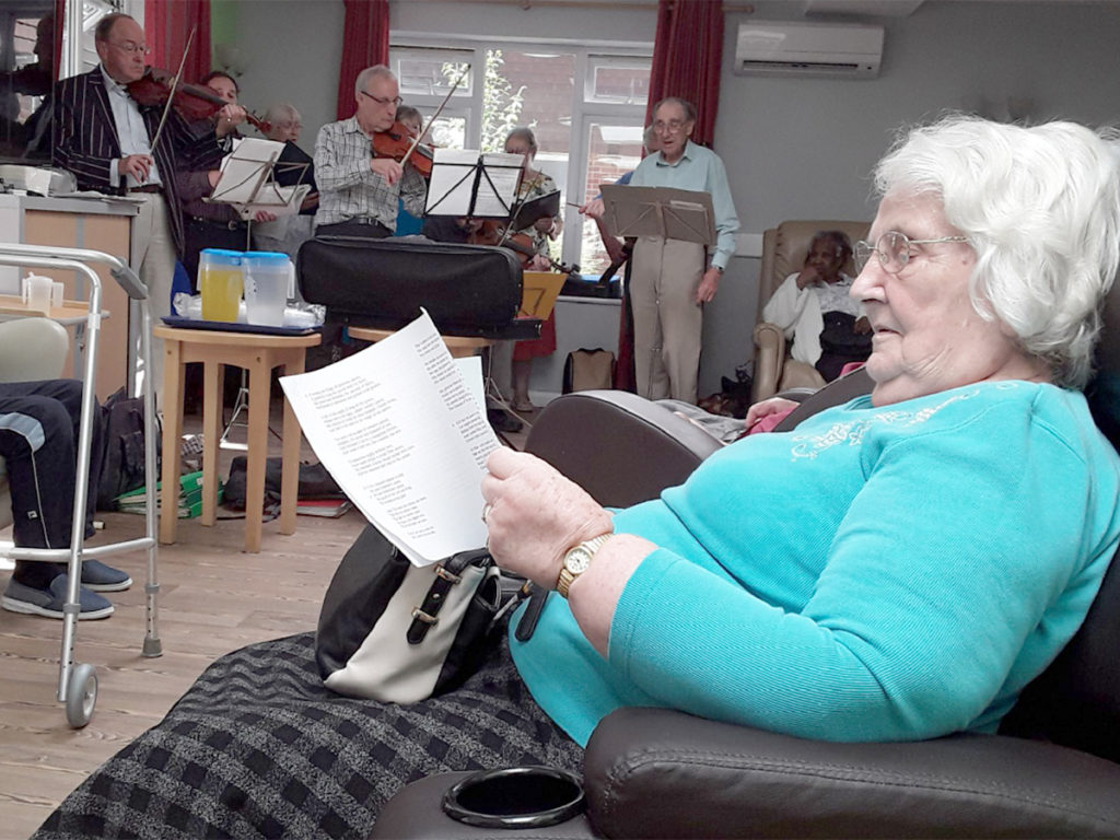 Abbotsleigh Care Home resident with a song sheet singing along to a local choir