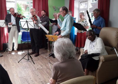Residents at Abbotsleigh Care Home captivated by a local choir singing and playing musical instruments