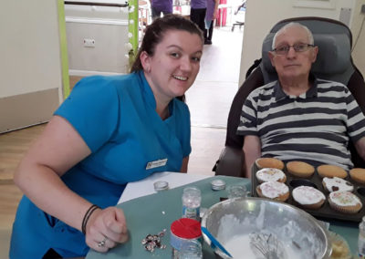 Abbotsleigh Care Home Activities Coordinator icing and decorating fairy cakes with a male resident