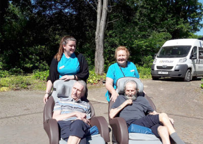 Abbotsleigh Care Home Activities Coordinators walking two chair-bound residents around the beautiful grounds outside