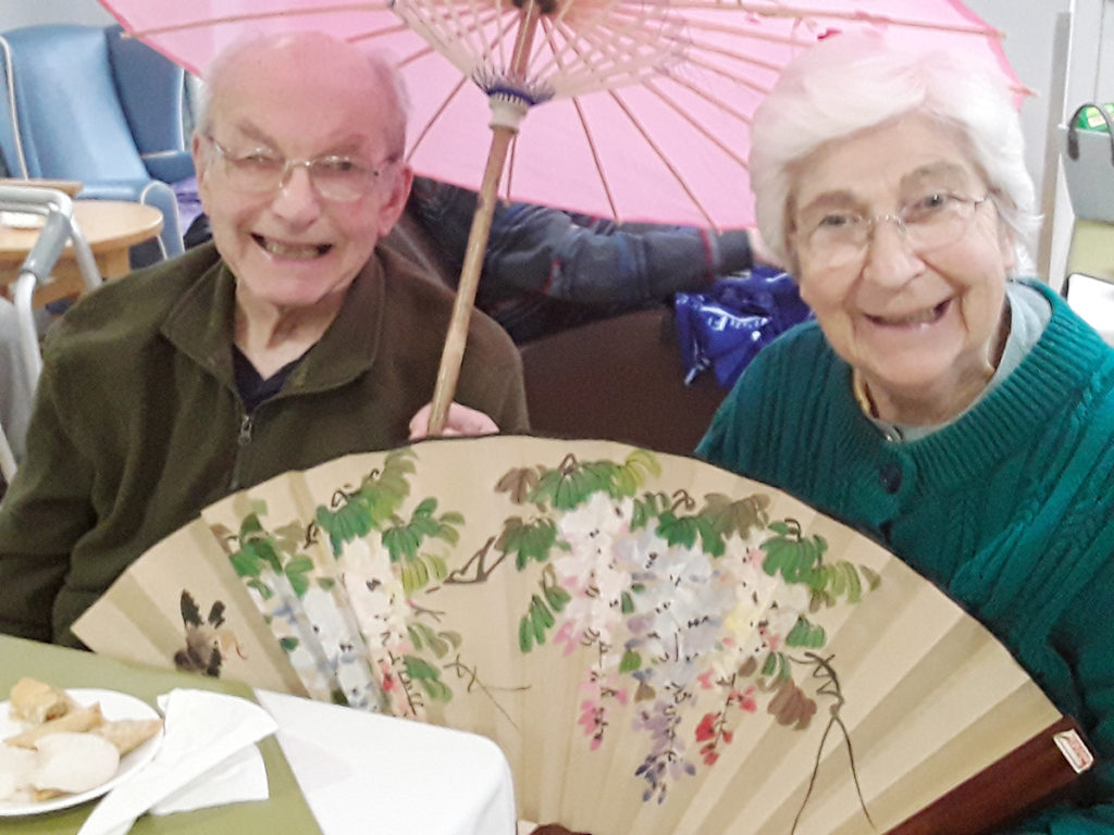 Lady and gentlemen resident of Abbotsleigh Care Home, holding a Chinese umbrella and fan