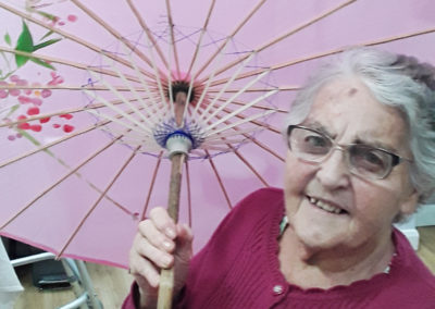 Lady resident standing with a Chinese umbrella at Abbotsleigh Care Home
