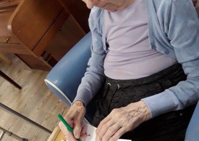 Lady resident sitting at a table colouring in a picture of a bird