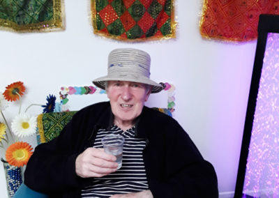 Gentleman resident sitting in a hat with a glass of water, enjoying a Namaste session
