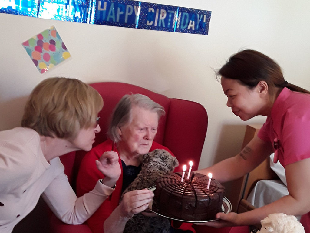 Lady resident receiving a chocolate birthday cake with candles