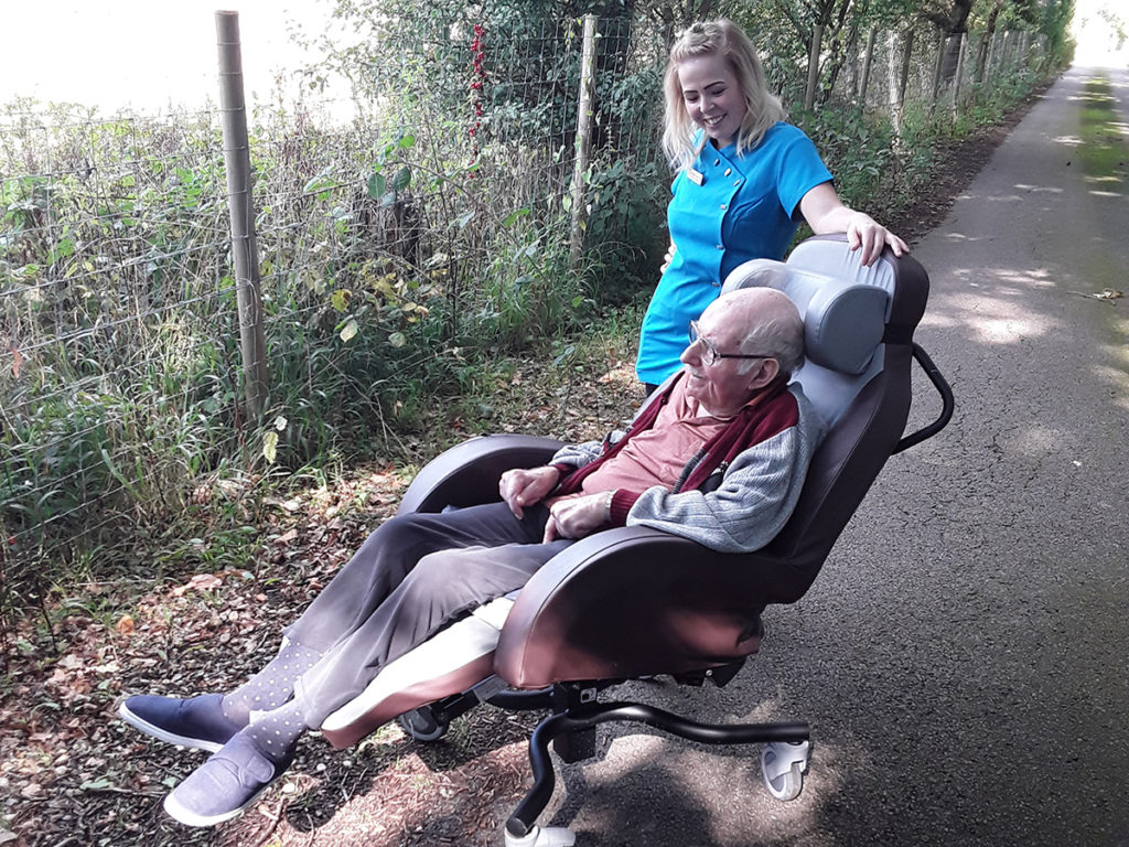 A male resident and staff member from Abbotsleigh Care Home taking a peaceful stroll around the grounds