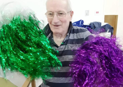 Gentleman resident smiling with green and purple pompoms