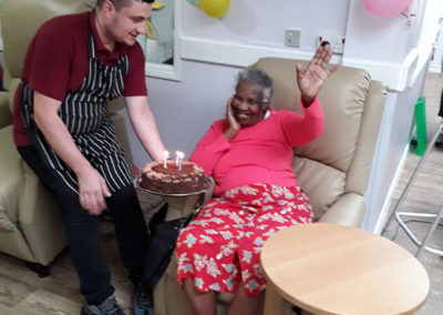 Lady resident receiving a birthday cake at Abbotsleigh Care Home