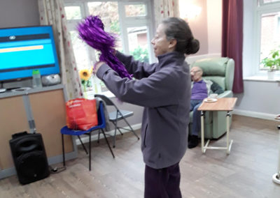 Lady resident at Abbotsleigh Care Home dancing with a glittery pom pom