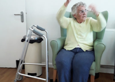 Lady stretching her arms up during a seated exercise class