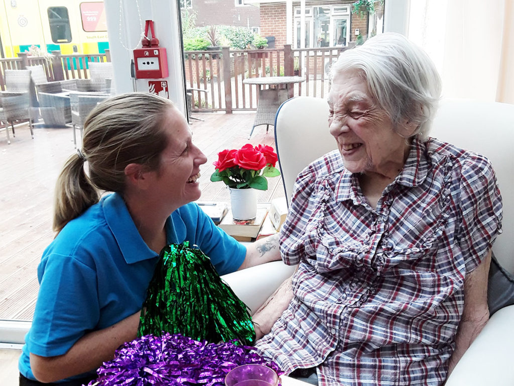 Staff member with a resident smiling over some glittery pom-poms