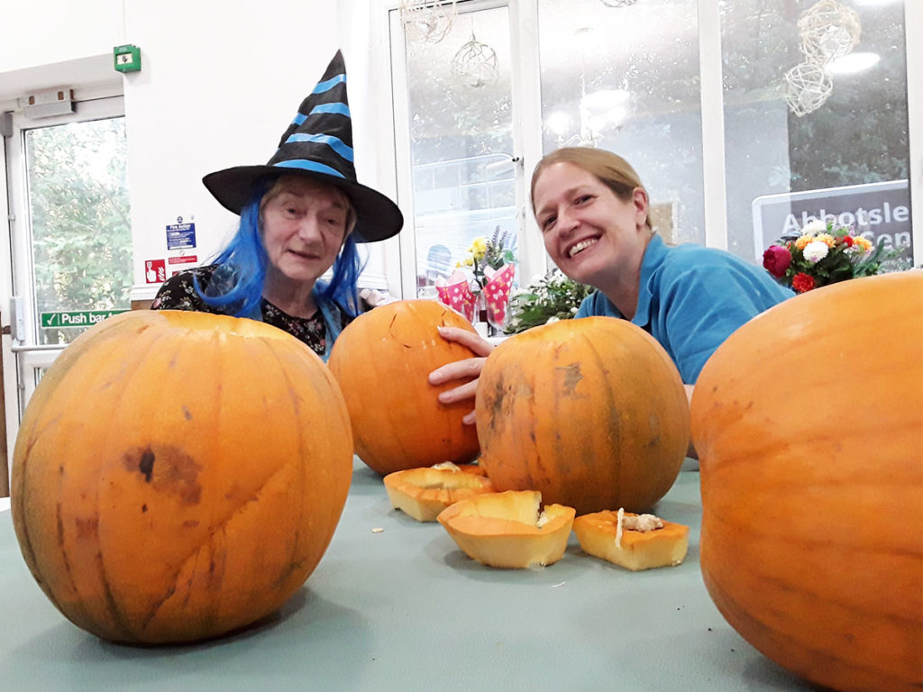Staff member and resident carving pumpkins together