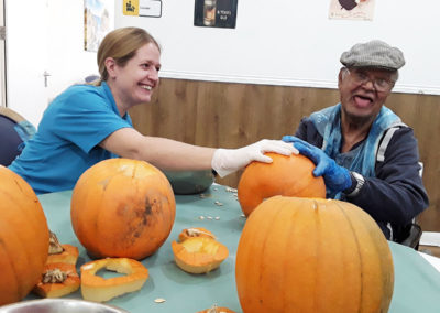 Staff member and gentleman resident carving pumpkins together