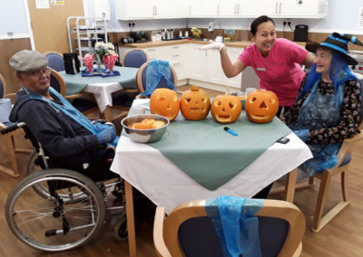 Staff member and residents carving pumpkins