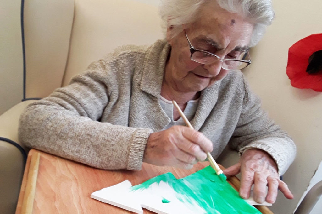 A lady resident painting a Christmas tree decoration at Abbotsleigh Care Home