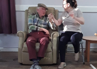 Resident and carer sitting together and enjoying the live music at Abbotsleigh Care Home