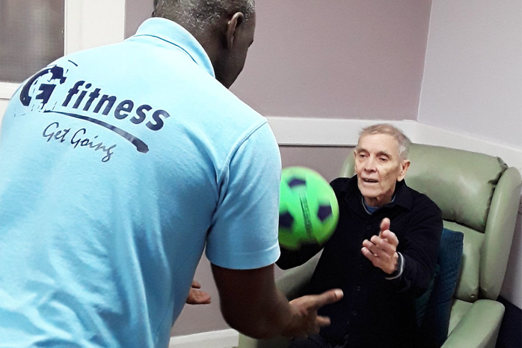 Henry from G-Fitness throwing a ball for a resident during an exercise class