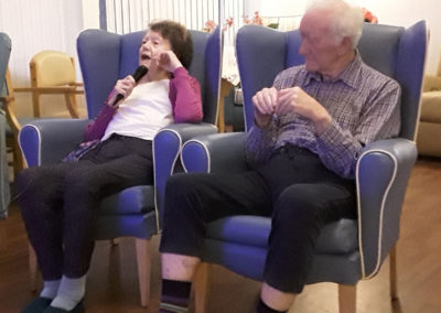 Residents enjoying karaoke with a mcirophone at Abbotsleigh Care Home