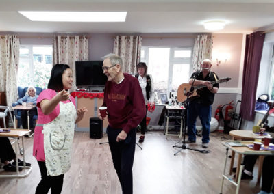 Male resident and staff member dancing to a live music group in the lounge at Abbotsleigh