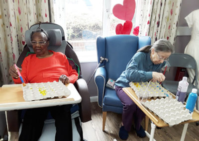 Two lady residents painting egg boxes for Easter decorations at Abbotsleigh Care Home