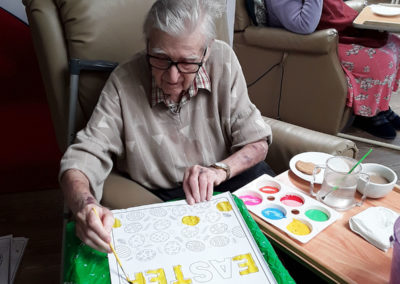 Gentleman resident painting an Easter picture at Abbotsleigh Care Home