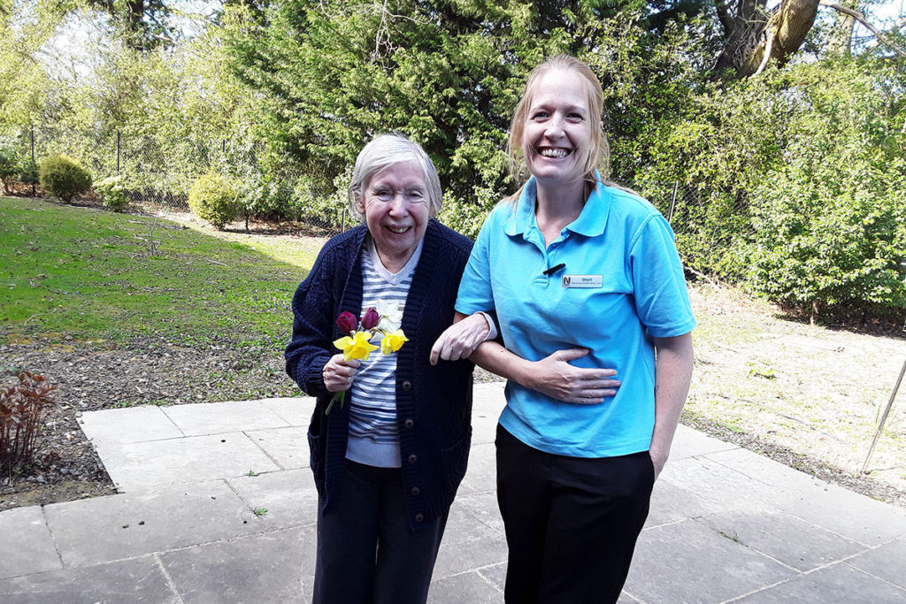 Resident and staff member walking together in the garden at Abbotsleigh Care Home