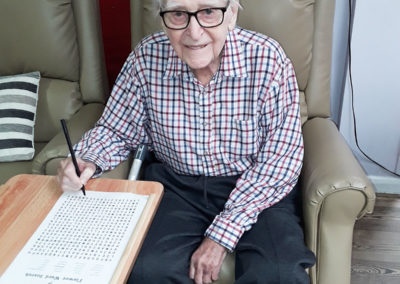 Gentleman resident doing a wordsearch at Abbotsleigh Care Home