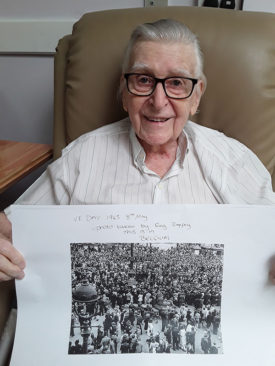 Resident holding a VE Day photo he had taken in Belgium
