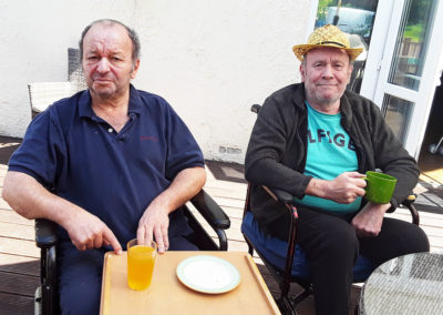 Two male residents sitting out on the decked area at Abbotsleigh Care Home