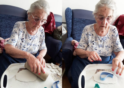 Lady resident cutting out clay birds for a wind chime