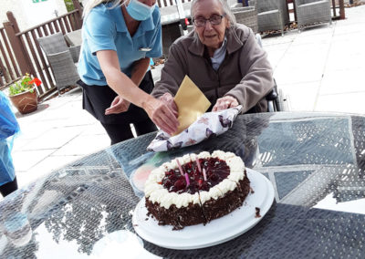 A resident admiring her cake on her birthday outside at Abbotsleigh Care Home